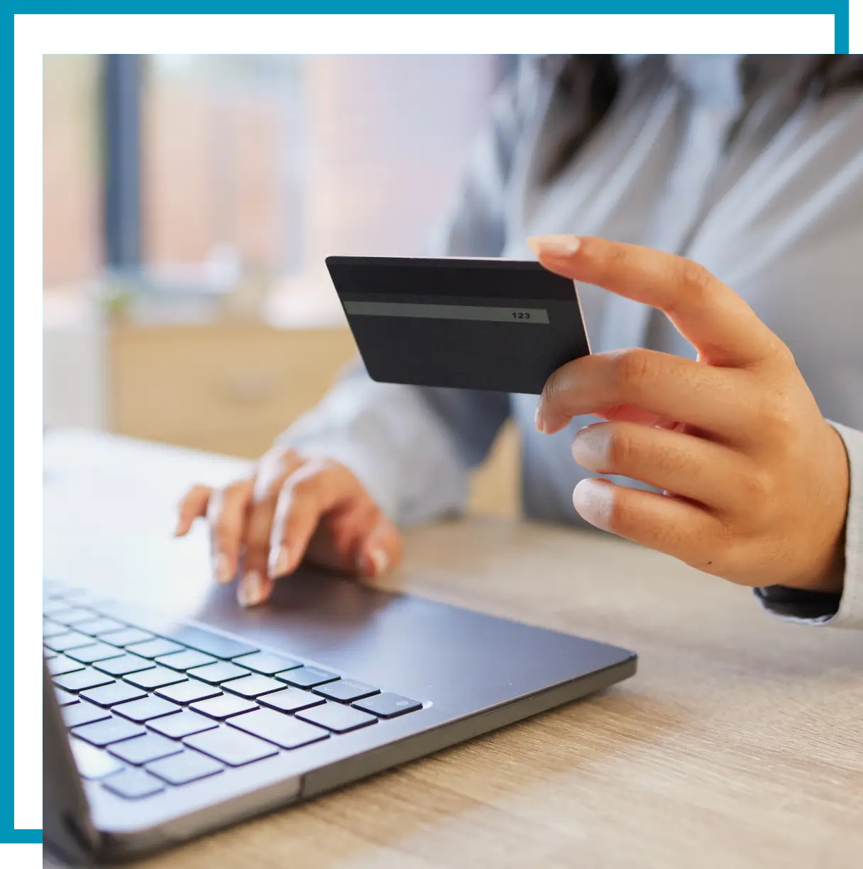 Hand holding a credit card near laptop